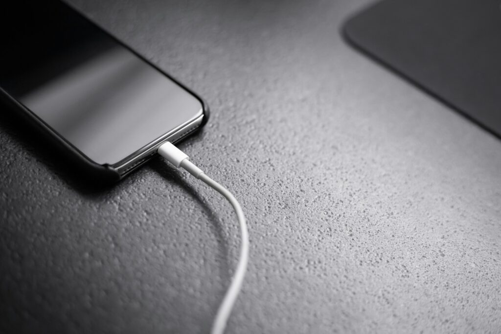 A smartphone plugged into a charging cable, illustrating the battery capacity gap between U.S. and Chinese Android phones
