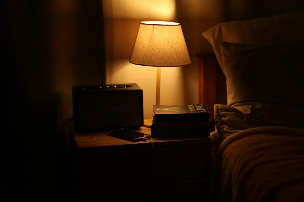Bedside nightstand lit by a lamp, the spot where most people rely on an Android phone alarm to wake them up