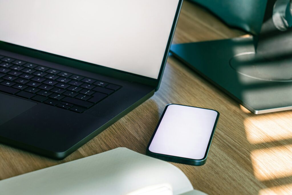A laptop and smartphone side by side on a desk, representing sending Chrome tabs between devices