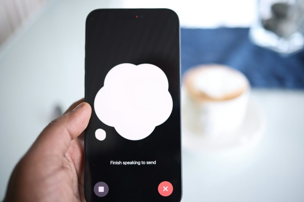 Hand holding a smartphone with an AI chat speech bubble on screen, illustrating Gemini replacing Google Assistant on Android