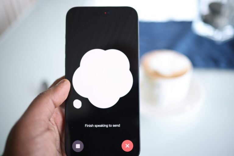 Hand holding a smartphone with an AI chat speech bubble on screen, illustrating Gemini replacing Google Assistant on Android