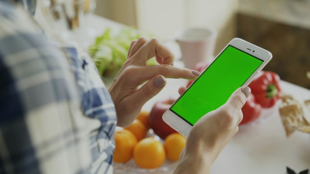 A person checking a shared list on an Android phone in the kitchen