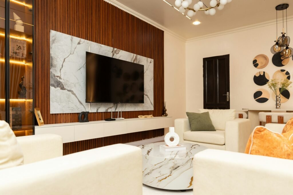Wall-mounted TV in a modern living room with white sofas, illustrating TCL's new flush-mount Designer Series Google TVs