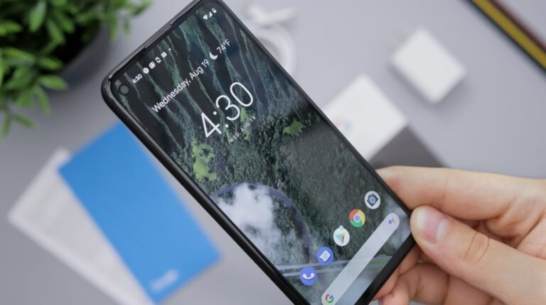 A person holding a black Android smartphone, the kind of phone where Google's automatic phone number verification setting is switched on by default