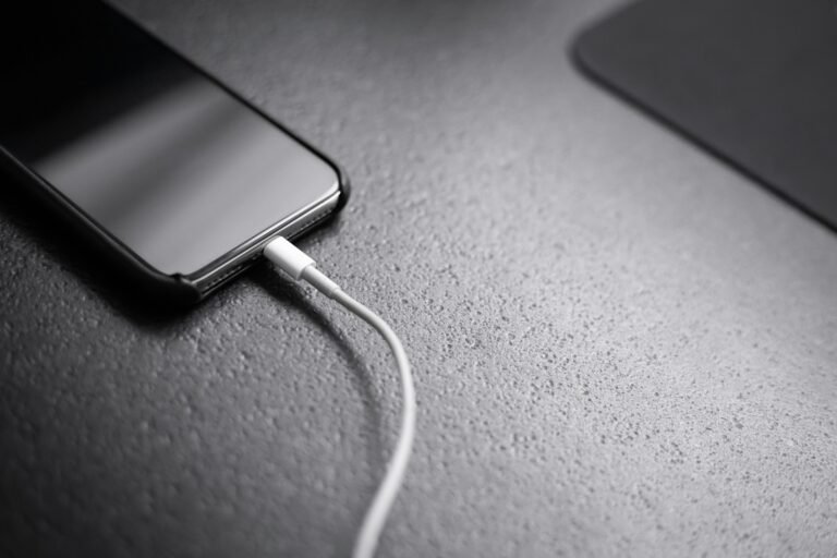 A smartphone plugged into a charger, illustrating Galaxy S24 and S25 battery drain after the One UI 9 update