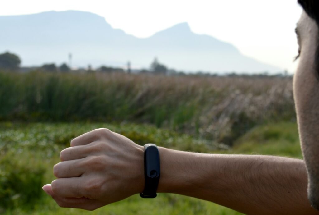 A man checking a black fitness tracker on his wrist after a workout, the kind of session Fitbit Air will now detect automatically