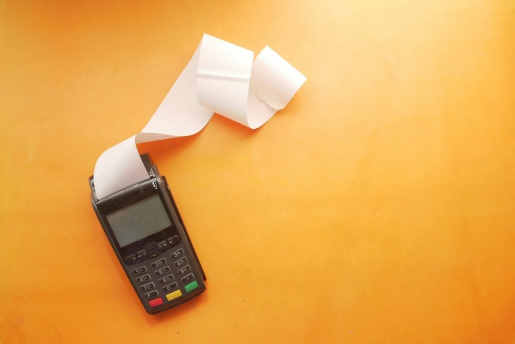 A card payment terminal printing a long paper receipt, the kind Google Wallet can now scan and store on Android