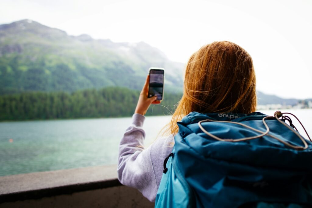 A traveler photographs the Swiss Alps with her phone, the kind of remote spot where Pixel Satellite SOS is meant to help when there is no cell signal
