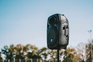 A portable wireless Bluetooth speaker outdoors with trees in the background