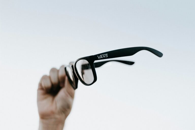 A hand holding up a pair of glasses, illustrating XREAL's Aura Android XR smart glasses