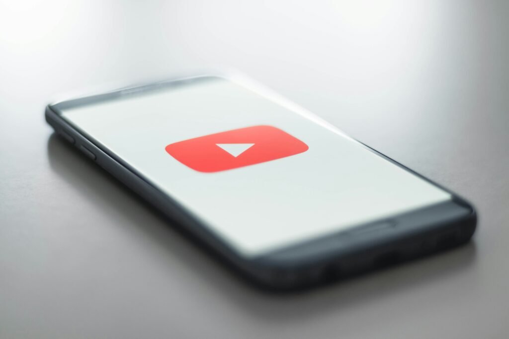 A smartphone showing the YouTube app, which is moving its Subscriptions feed from the bottom bar to the top of Home